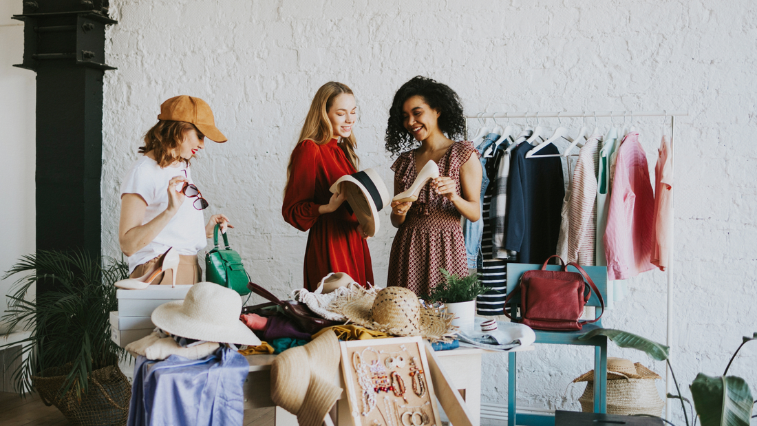Tre amiche fanno shopping in un negozio di abbigliamento e accessori vintage.