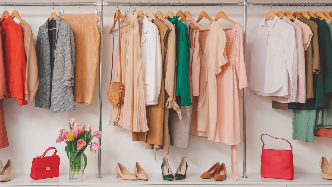 Guardaroba a vista con collezione di abbigliamento donna, abiti primaverili, gonne plissettate, blazer, scarpe décolleté e borse rosse.